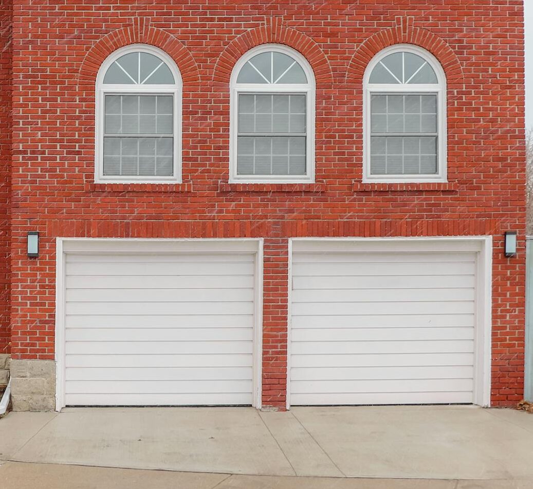 Red brick house exterior in Toronto with arched windows, chimney, and double garage.