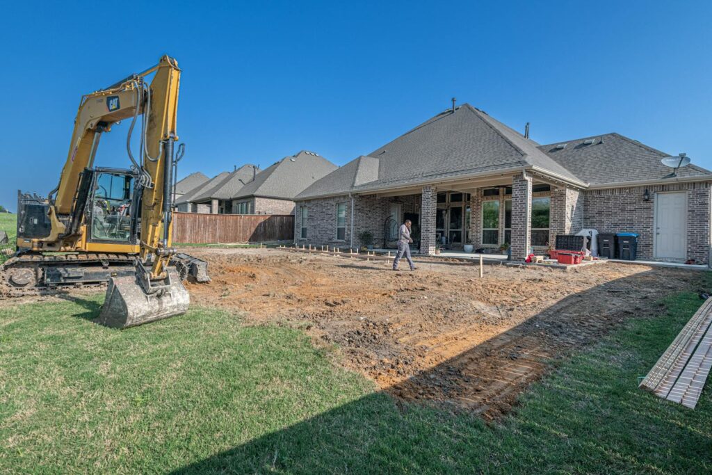 A construction site for a new patio in a Texas backyard with heavy machinery.