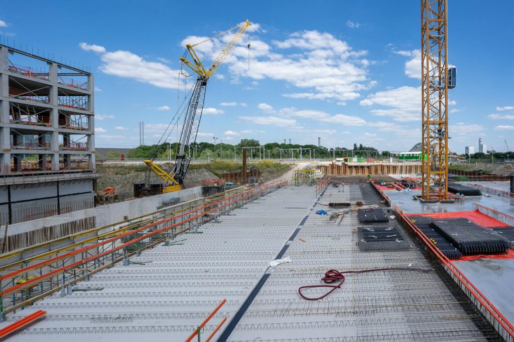 View of a busy construction site with cranes and building structure under clear sky.
